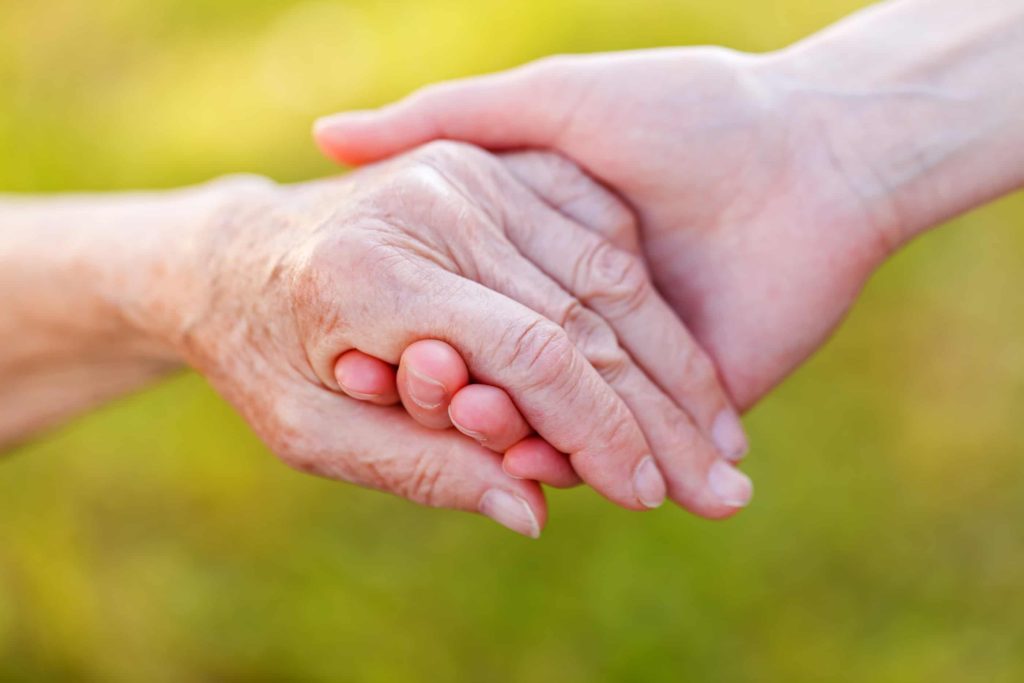 SCi Homecare's caregiver with senior's hand compassionate
