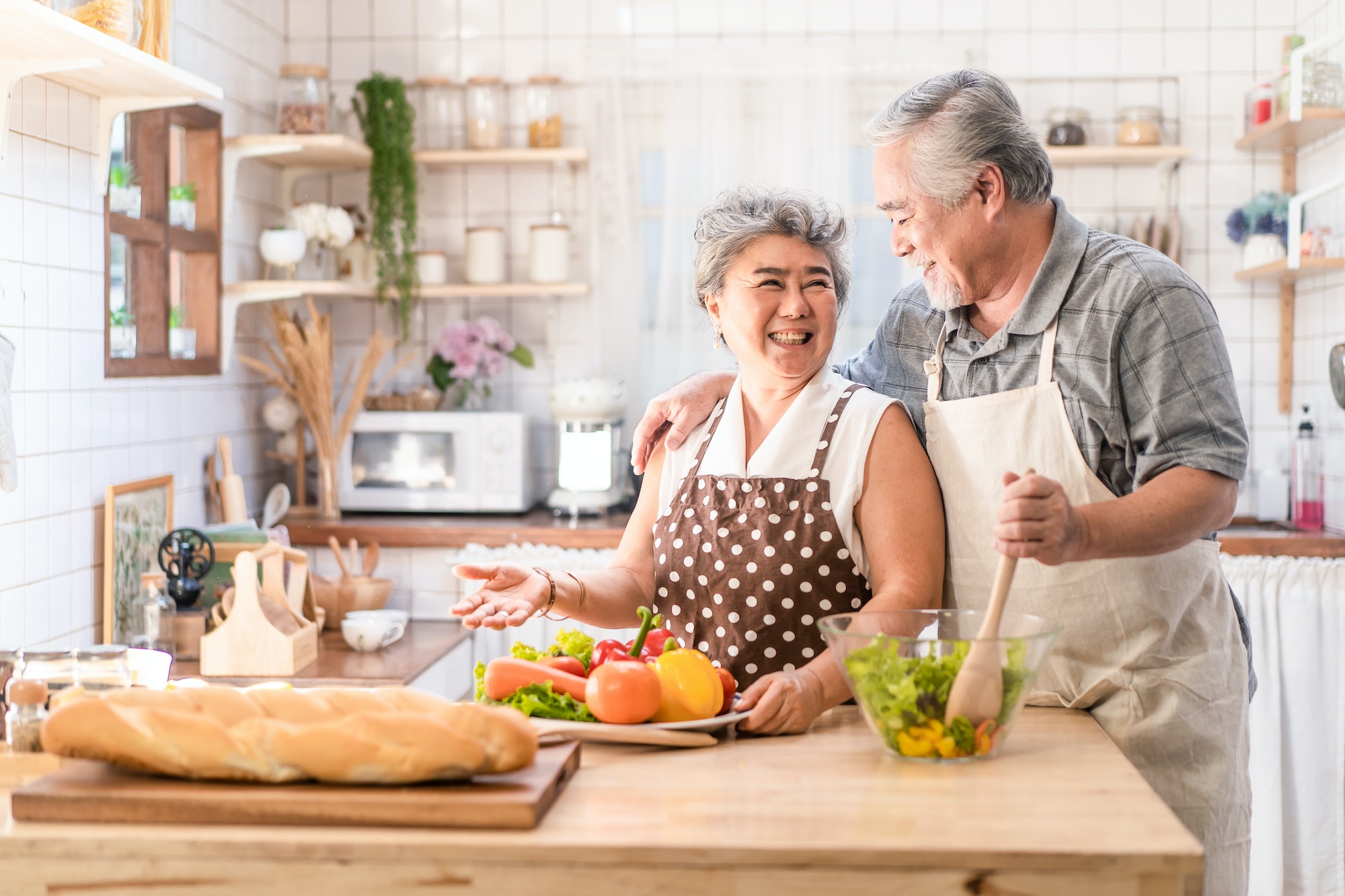 Couple senior Asian elder people cook salad dish with happiness, enjoy retirement life together.