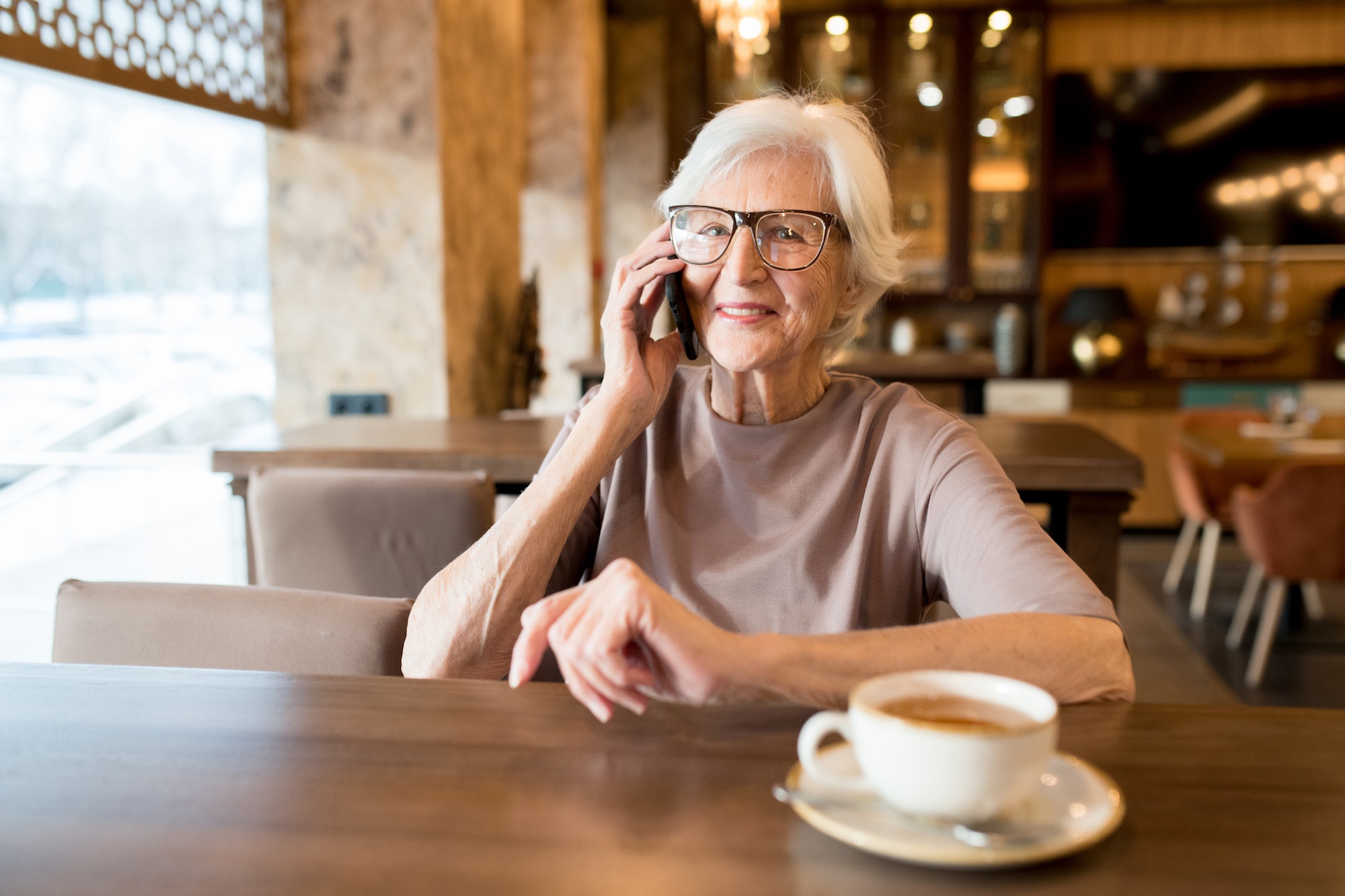 Positive senior entrepreneur talking by phone
